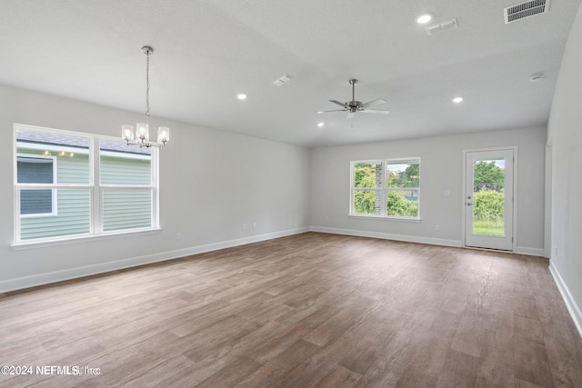 spare room featuring a textured ceiling, light hardwood / wood-style floors, and ceiling fan with notable chandelier