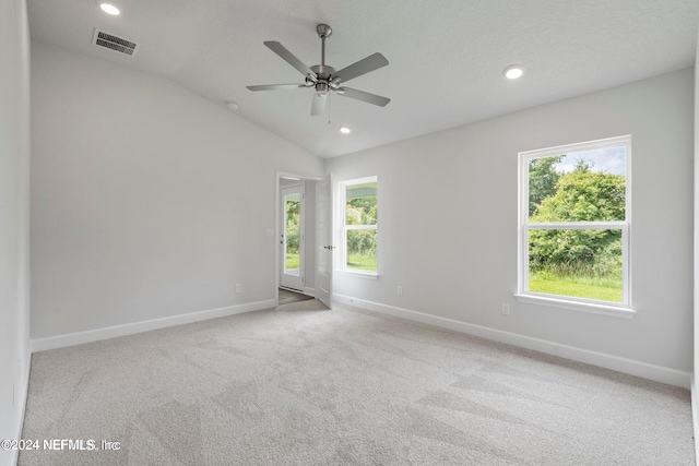 carpeted spare room featuring ceiling fan and vaulted ceiling