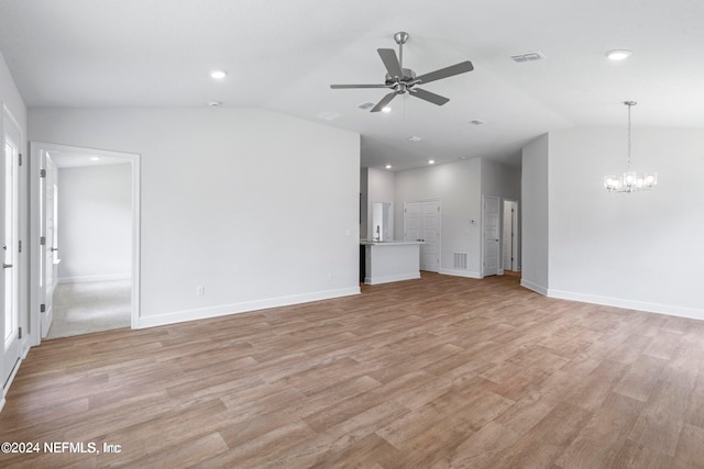 unfurnished living room with vaulted ceiling, ceiling fan with notable chandelier, and light hardwood / wood-style flooring