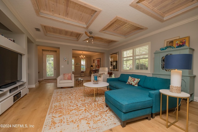 living room featuring wood-type flooring, a tray ceiling, ceiling fan with notable chandelier, and ornamental molding