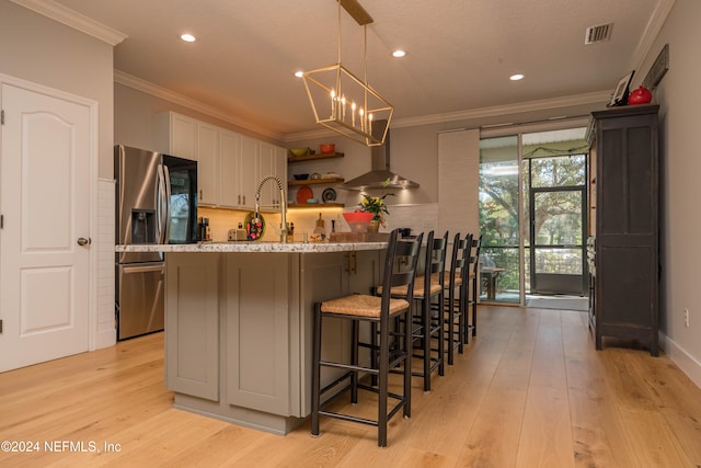 kitchen featuring white cabinetry, light hardwood / wood-style floors, stainless steel fridge with ice dispenser, and a breakfast bar