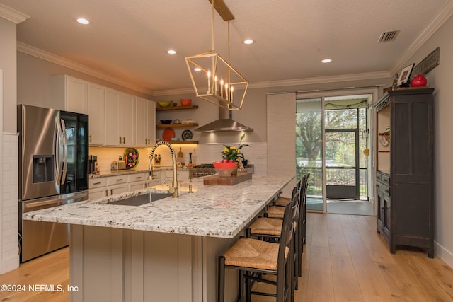 kitchen featuring light hardwood / wood-style floors, white cabinetry, a kitchen breakfast bar, hanging light fixtures, and stainless steel fridge