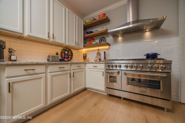 kitchen featuring light stone counters, double oven range, crown molding, island exhaust hood, and light wood-type flooring