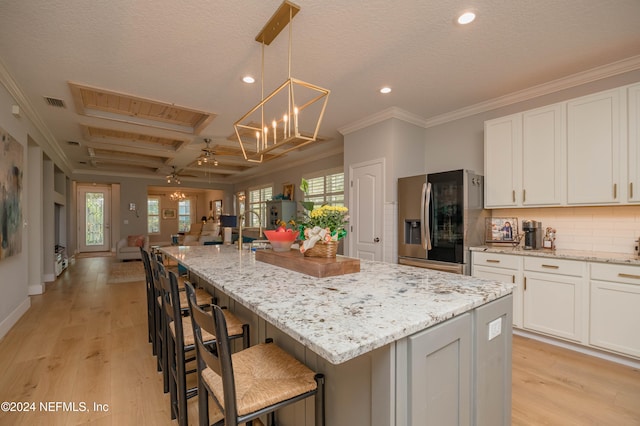 kitchen with light hardwood / wood-style floors, stainless steel fridge, and a spacious island