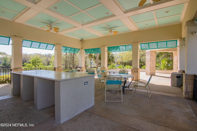 unfurnished sunroom featuring ceiling fan, beam ceiling, and coffered ceiling