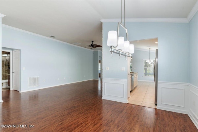 unfurnished dining area with ceiling fan with notable chandelier, light hardwood / wood-style floors, lofted ceiling, and crown molding