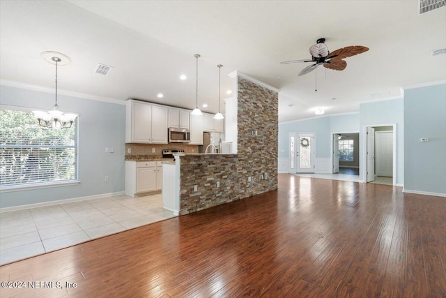 kitchen featuring appliances with stainless steel finishes, ceiling fan with notable chandelier, hanging light fixtures, light hardwood / wood-style flooring, and white cabinets