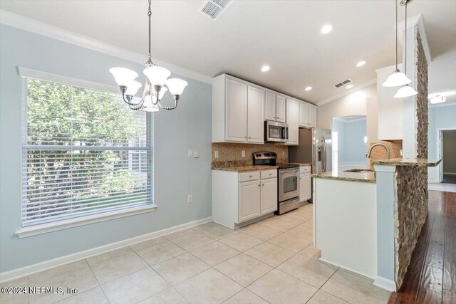 kitchen featuring plenty of natural light, white cabinetry, hanging light fixtures, and stainless steel appliances