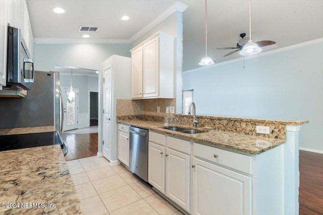 kitchen with white cabinets, sink, ornamental molding, light wood-type flooring, and appliances with stainless steel finishes