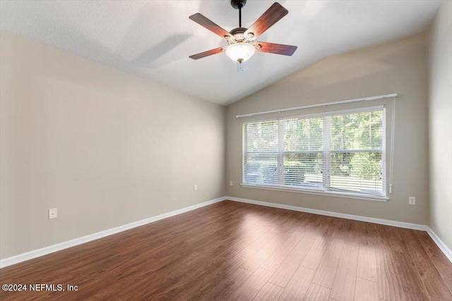 empty room with dark wood-type flooring, vaulted ceiling, ceiling fan, and plenty of natural light