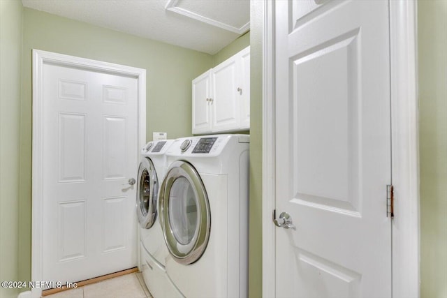 laundry area featuring cabinets, separate washer and dryer, a textured ceiling, and light tile patterned floors