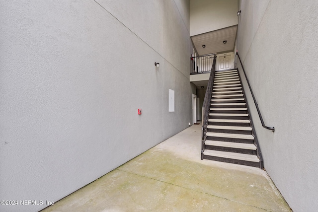 stairway featuring concrete flooring and a towering ceiling