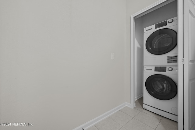 laundry room featuring stacked washer and dryer and light tile patterned floors