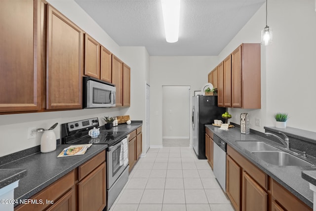 kitchen featuring light tile patterned flooring, stainless steel appliances, a textured ceiling, pendant lighting, and sink