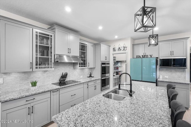 kitchen with gray cabinetry, tasteful backsplash, stainless steel appliances, sink, and a kitchen breakfast bar