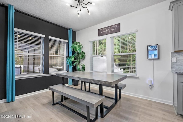 dining room featuring an inviting chandelier, a textured ceiling, and light hardwood / wood-style flooring