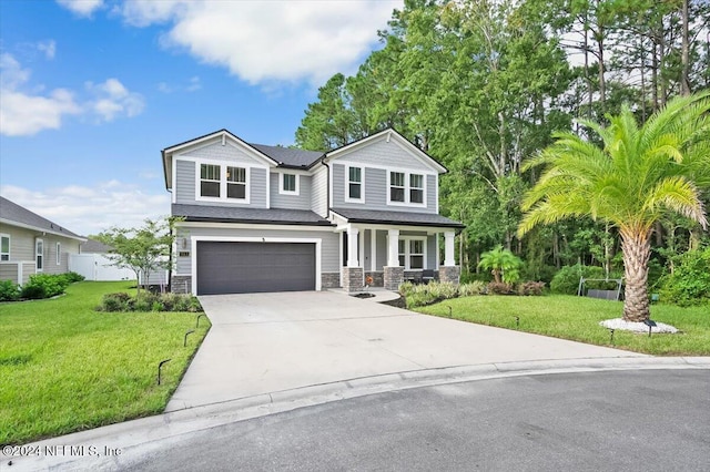 view of front of home with covered porch, a garage, and a front yard