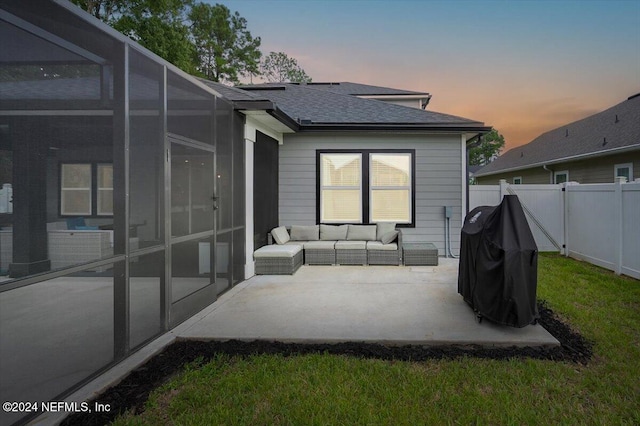 back house at dusk featuring a patio, outdoor lounge area, and a lanai