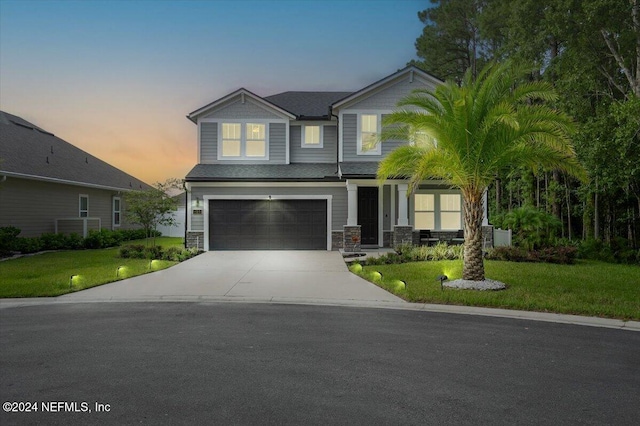 craftsman inspired home with covered porch, a garage, and a yard