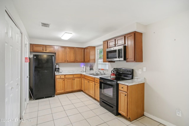 kitchen with black appliances, sink, and light tile patterned floors