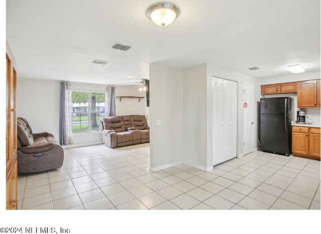 kitchen featuring black fridge, light tile patterned flooring, and ceiling fan