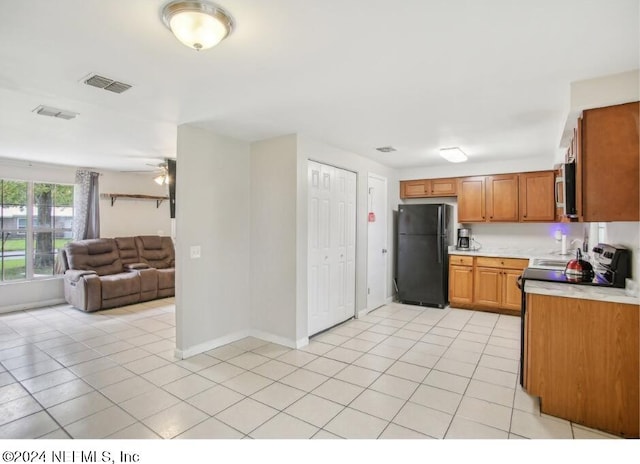 kitchen with light tile patterned flooring, ceiling fan, and black refrigerator