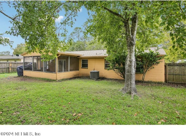 rear view of property with central AC, a sunroom, and a yard