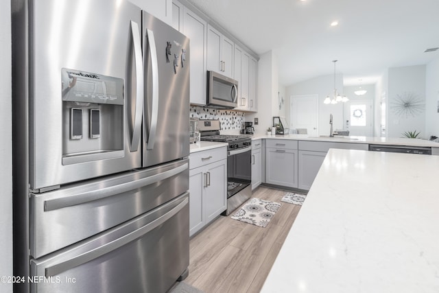 kitchen featuring gray cabinetry, stainless steel appliances, backsplash, sink, and light hardwood / wood-style floors