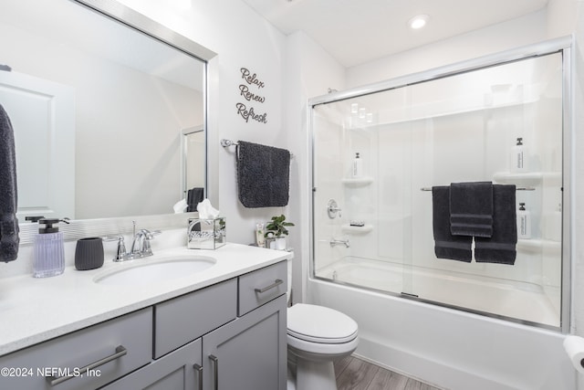 full bathroom with shower / bath combination with glass door, hardwood / wood-style flooring, toilet, and vanity