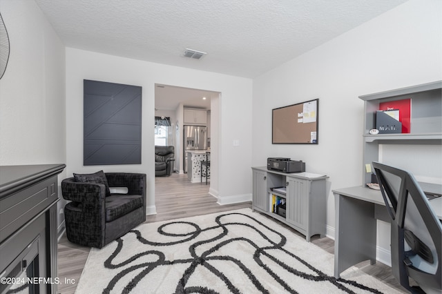 office with a textured ceiling and light hardwood / wood-style flooring