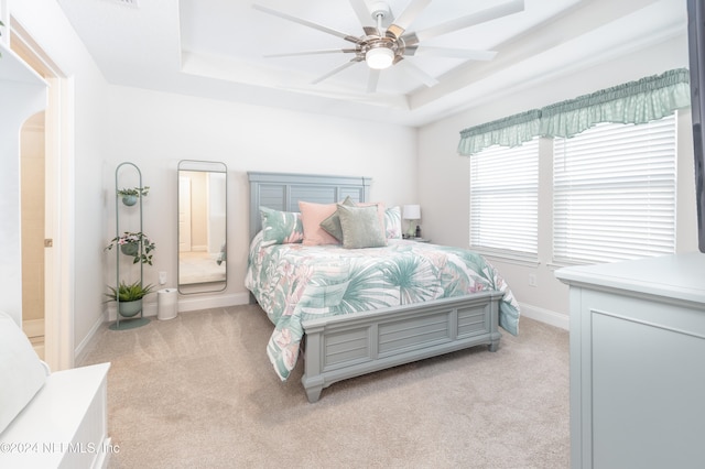 carpeted bedroom with ceiling fan and a raised ceiling