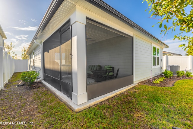 view of property exterior featuring central AC, a sunroom, and a yard