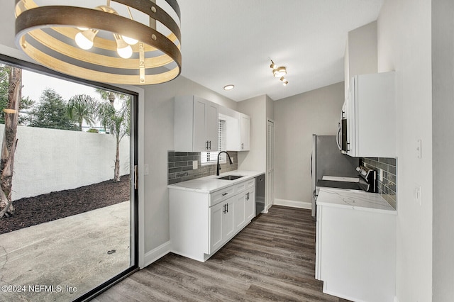 kitchen with stainless steel appliances, dark wood-type flooring, white cabinets, decorative backsplash, and sink