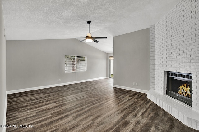 unfurnished living room with vaulted ceiling, a textured ceiling, dark hardwood / wood-style floors, ceiling fan, and a fireplace