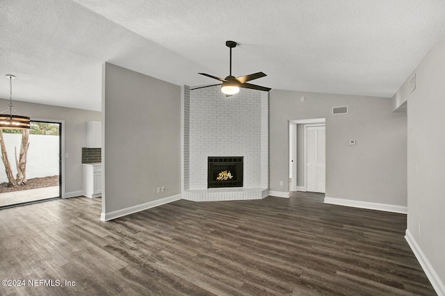 unfurnished living room with a brick fireplace, dark hardwood / wood-style flooring, lofted ceiling, and ceiling fan