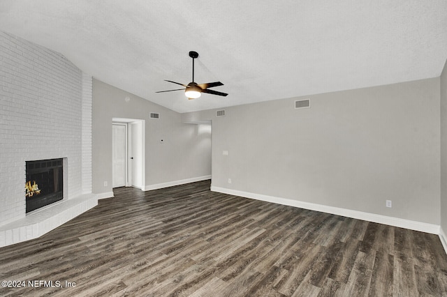 unfurnished living room with ceiling fan, a textured ceiling, lofted ceiling, a brick fireplace, and dark hardwood / wood-style flooring