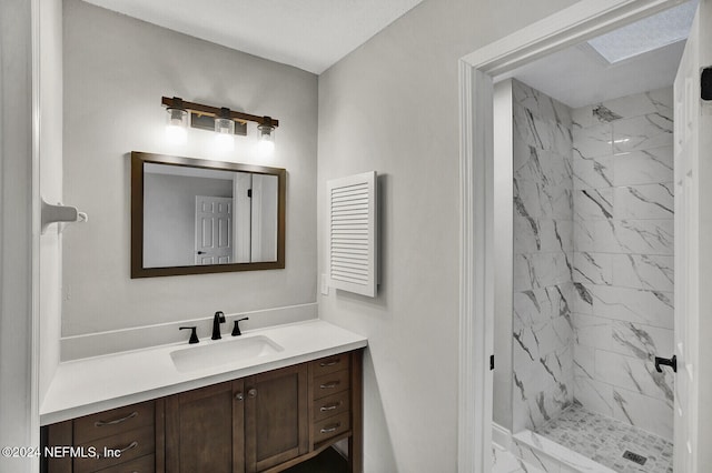 bathroom featuring tiled shower, vanity, and a skylight