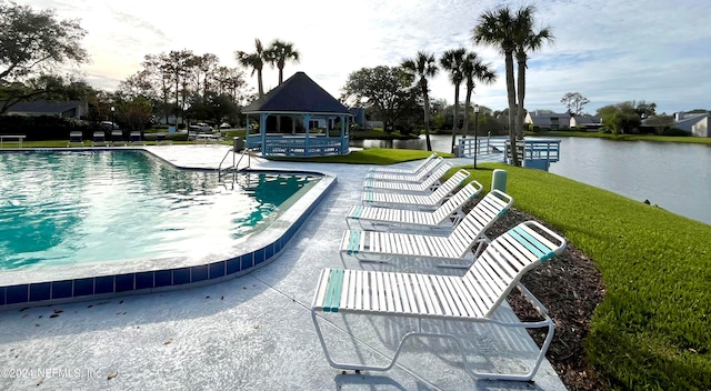 view of swimming pool with a patio, a water view, a yard, and a gazebo