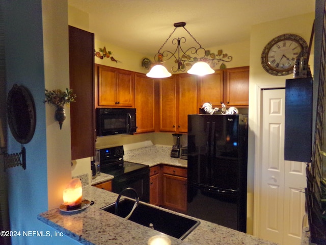 kitchen featuring kitchen peninsula, black appliances, sink, light stone countertops, and decorative light fixtures