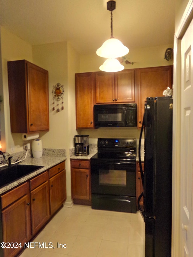 kitchen featuring sink, black appliances, light stone counters, light tile patterned floors, and hanging light fixtures