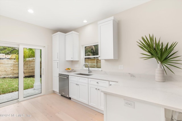 kitchen with light stone counters, stainless steel dishwasher, sink, light hardwood / wood-style floors, and white cabinetry