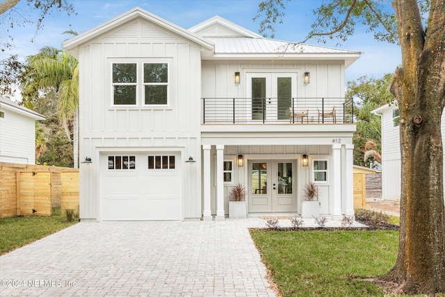 modern farmhouse style home featuring french doors, a balcony, a garage, and a front lawn