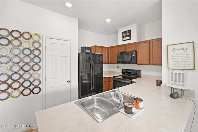 kitchen featuring black appliances, kitchen peninsula, sink, and a textured ceiling