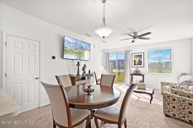 carpeted dining area with a textured ceiling and ceiling fan