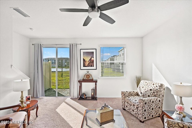 sitting room with a textured ceiling, light colored carpet, and ceiling fan