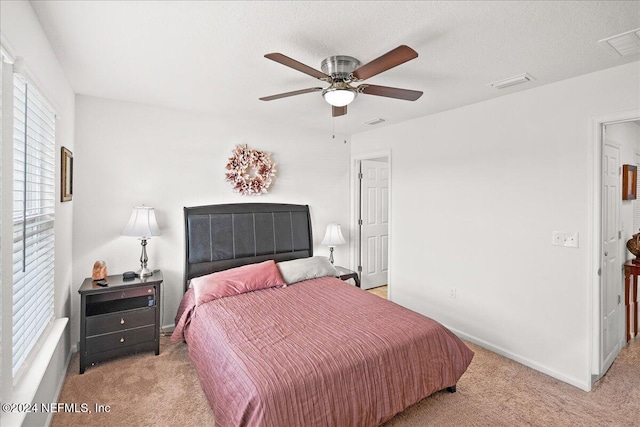 bedroom with ceiling fan, a textured ceiling, and light colored carpet