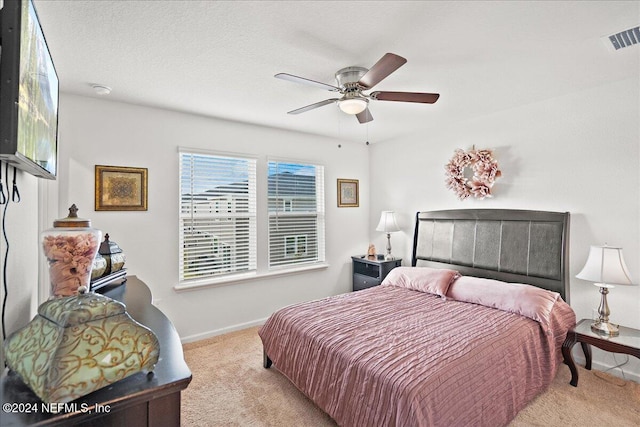 bedroom with a textured ceiling, light carpet, and ceiling fan