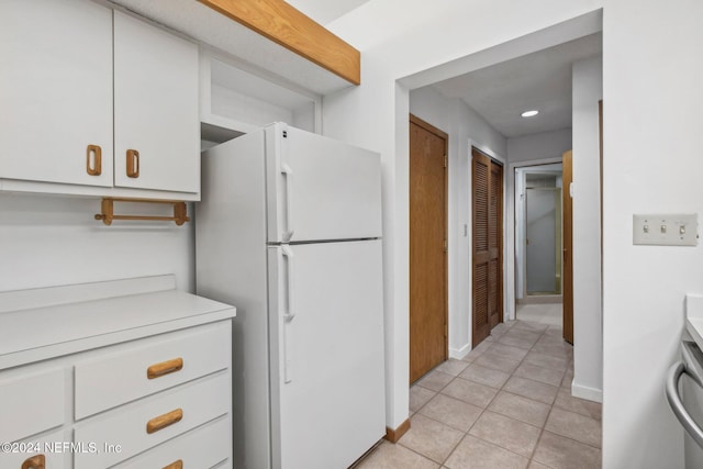 kitchen with white cabinets, white fridge, and light tile patterned flooring