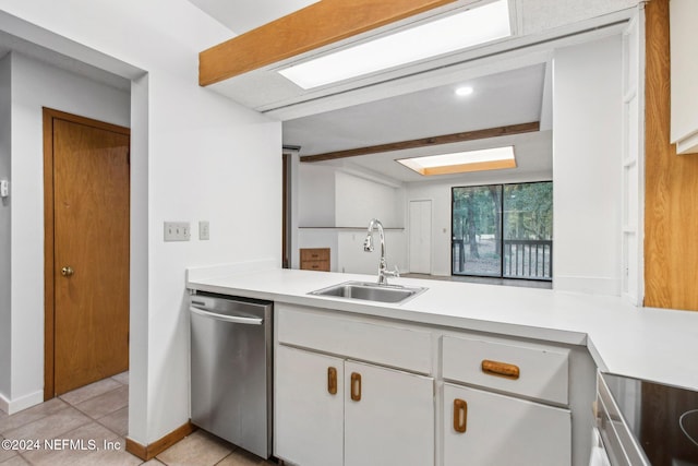 kitchen featuring a skylight, white cabinetry, sink, stainless steel appliances, and light tile patterned flooring