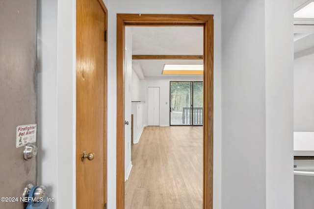 hall with beam ceiling and light wood-type flooring